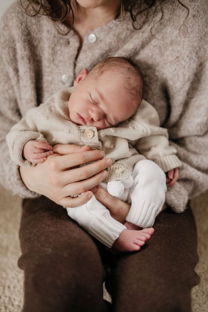 baby slaapt tijdens newbornshoot Baby ligt heerlijk te slapen op mama's schoot