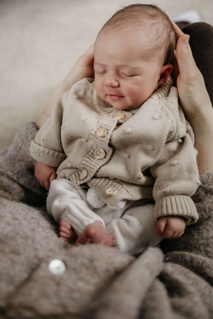 Baby lacht in haar slaap terwijl ze. wordt vastgehouden door mama.