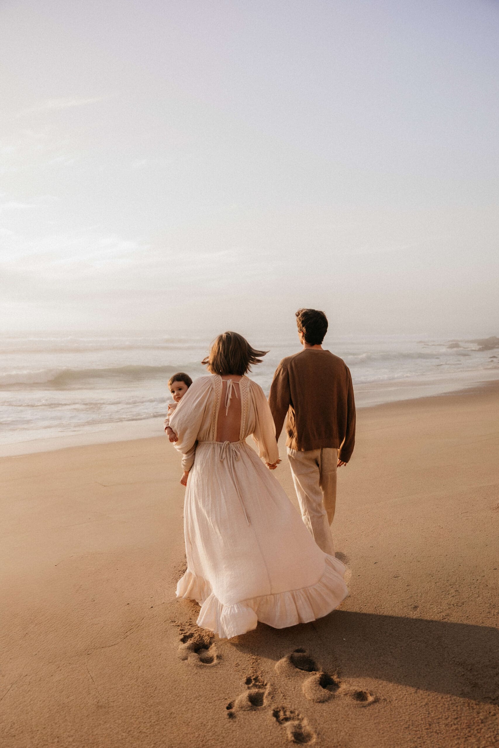 gezin loopt hand in hand over het strand tijdens golden hour