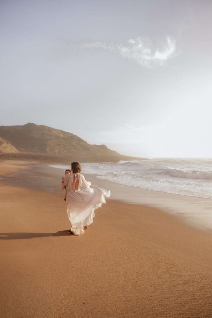 Vrouw in een prachtige jurk op het strand tijdens zonsondergang