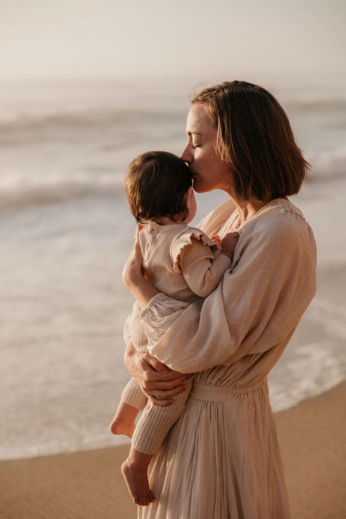 Mama kust haar kind op het strand